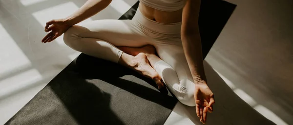 Calm young woman meditating, sitting on lotus pose at beautiful yoga studio. young attractive woman sitting in Ardha Padmasana exercise, Lotus pose on meditation, closed eyes, wearing sportswear