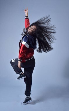 Güzel, genç Asyalı bayan dansçı, uzun saç fiskesi fotoğraflı. Çekici, hayalperest, neşeli, rüzgar esintisi yapan, parlak mavi bir arka planda izole edilmiş, uzun boylu bir kadının vücut ölçüleri.