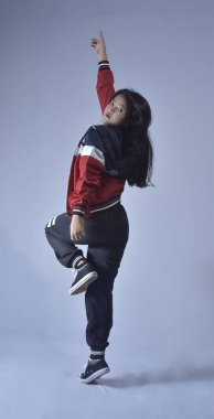 Güzel, genç Asyalı bayan dansçı, uzun saç fiskesi fotoğraflı. Çekici, hayalperest, neşeli, rüzgar esintisi yapan, parlak mavi bir arka planda izole edilmiş, uzun boylu bir kadının vücut ölçüleri.