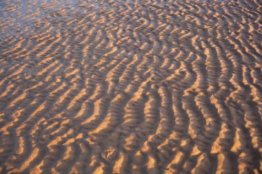 Altın saat boyunca kumda dalgalanmalar.