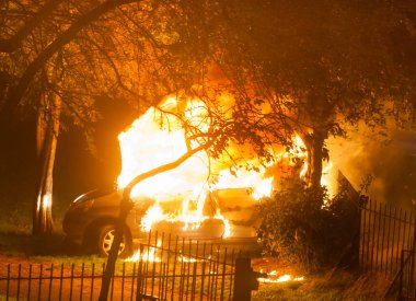 Halka açık bir parkta yanan terk edilmiş bir araba. Araba yanıyor, bir sürü alev ve duman..