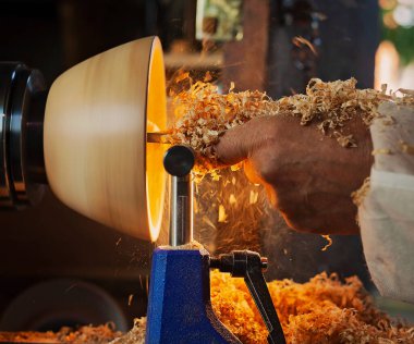Ahşap bir kase, ağaç torbasında bir adam tarafından döndürüldü. İşyerinde bir zanaatkar. Talaş uçuyor..