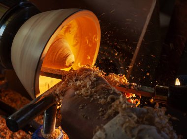 Ahşap bir kase, ağaç torbasında bir adam tarafından döndürüldü. İşyerinde bir zanaatkar. Talaş uçuyor..