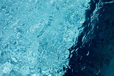 Mavi su yüzeyinde dalgalanmalar ve ışık yansımaları