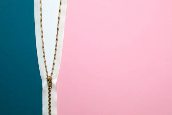 Yarı açık beyaz fermuarla bağlanmış mavi ve pembe renkli kağıtların üst görüntüsü. Kopyalama alanı ile yakın çekim.