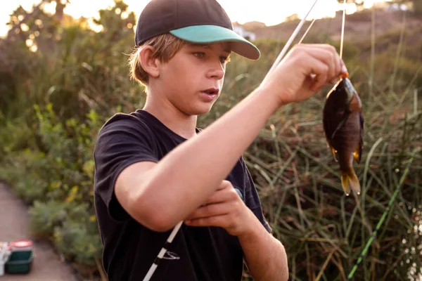 Smiling Teenage Boy Holding Catch Freshwater Fish In Hands Stock