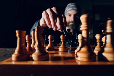 Genç ve yakışıklı bir adam karanlıkta satranç oynuyor.