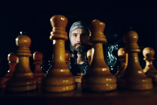 Jovem adulto bonito homem jogando xadrez no escuro com lado iluminado — Fotografia de Stock