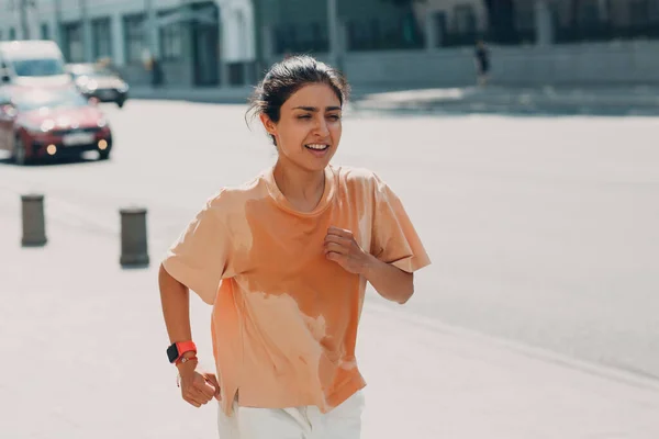 Genç Hintli kadın koşucu şehir caddesinde ıslak terli tişörtle koşuyor. — Stok fotoğraf
