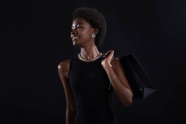 Siyah alışveriş torbaları tutan Afrikalı Amerikalı bir kadın. Piyasada ve Kara Cuma konseptinde indirim var..