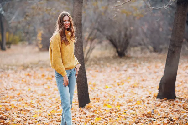 Młoda kobieta modelka w jesiennym parku z żółtymi liśćmi klonu liści. Moda jesienna. — Zdjęcie stockowe