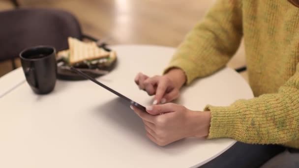 O tânără freelancer care lucrează cu tabletă PC în cafenea. Închide mâinile. — Videoclip de stoc