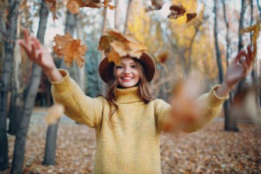 Sonbahar parkında sarı yapraklı genç bir manken. Sonbahar mevsimi modası.