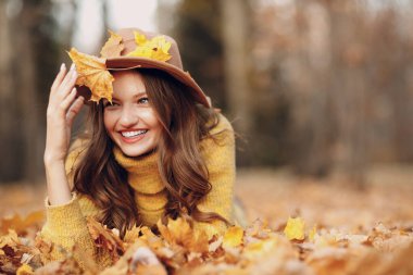 Sonbahar parkında sarı yapraklı genç bir manken. Sonbahar mevsimi modası.