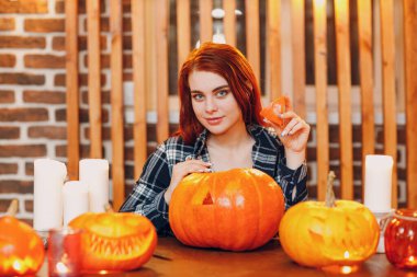 Cadılar Bayramı 'nda balkabağı yapan genç bir kadın. Bıçakla balkabaklarını kesen kadın elleri.