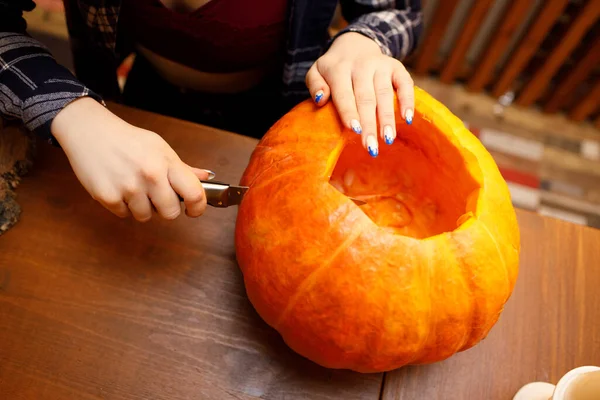 Ung kvinna som gör halloweenpumpa Jack-o-lantern. Kvinnliga händer skär pumpor med kniv. — Stockfoto