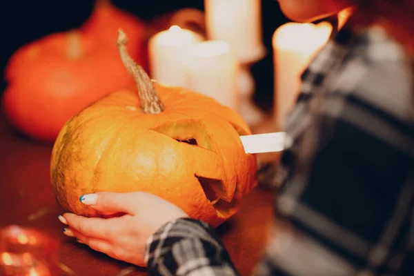 Молодая женщина делает тыквенный фонарь на Хэллоуин. Руки женщины режут тыквы ножом. — стоковое фото