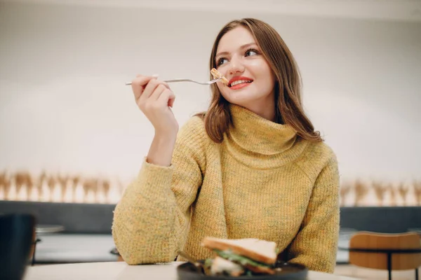 Wanita muda makan sandwich di kafe indoor — Stok Foto