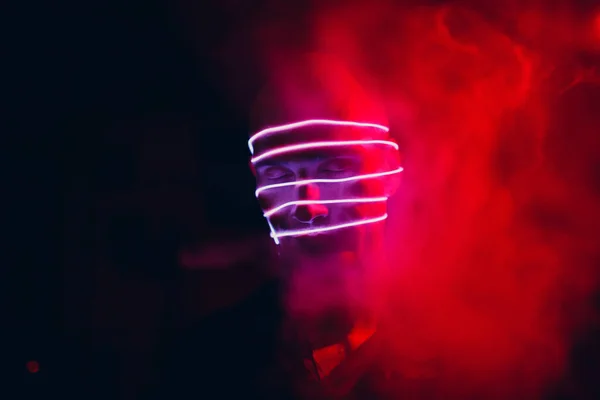 Potret manusia dengan tabung cahaya neon di wajahnya dalam gelap. Konsep cyberpunk dan virtual reality. — Stok Foto