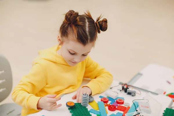 Маленькая девочка-детский конструктор проверяет техническую игрушку. Детский робот-конструктор. — стоковое фото