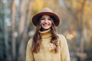 Sonbahar parkında sarı yapraklı genç bir manken. Sonbahar mevsimi modası.