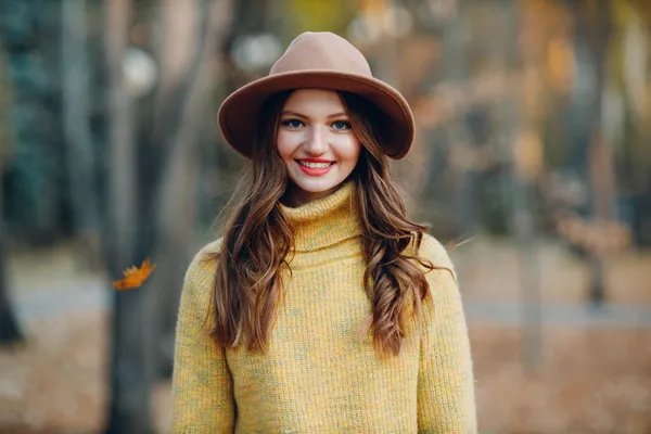 Modelo de mujer joven en el parque de otoño con hojas de arce follaje amarillo. Otoño temporada moda. — Foto de Stock