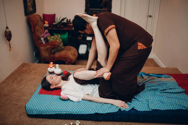 Thai man making classical thai massage procedure to young woman at beauty spa — Stock Photo, Image