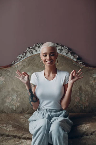 Millenial junge Frau mit kurzen blonden Haaren Porträt sitzt auf Vintage-Sofa. — Stockfoto