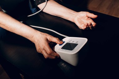 Yaşlı kadın evde kan basıncını ölçüyor. Yaşlıların sağlıklarına özen