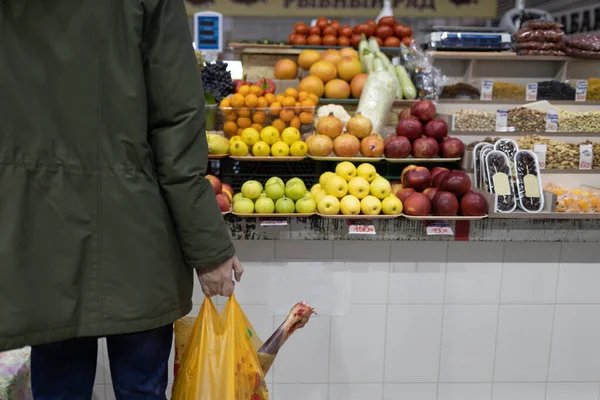 Dospělý muž se rozhodl koupit čerstvé ovoce na trhu a držet balíček s skopovým masem. Koncept nákupu potravin — Stock fotografie