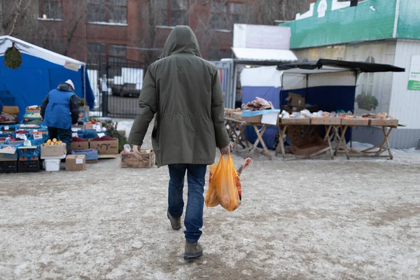 Dospělý muž chodí po ulici po nákupu potravin na trhu a drží balíček s skopovým masem. Koncept nákupu potravin — Stock fotografie