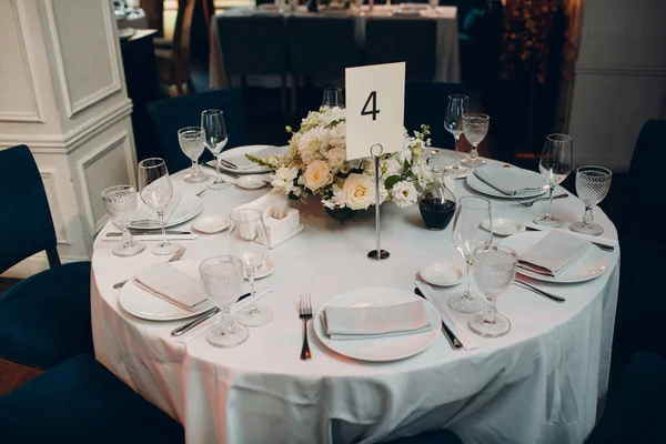 Ronde tafels in het restaurant met witte tafelkleden en witte boeketten van bloemen decor — Stockfoto