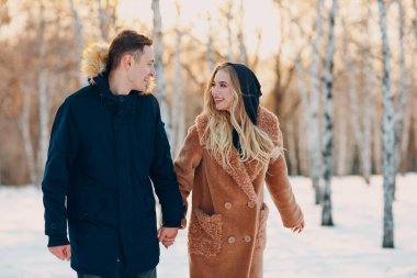 Sevgi dolu genç bir çift kış parkında yürüyor ve eğleniyor.