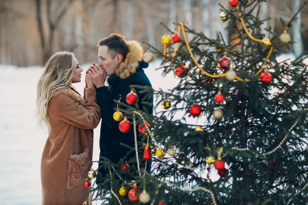 Young adult couple decorates christmas tree in winter forest. New year pine holiday party celebration concept. — Stock Photo, Image