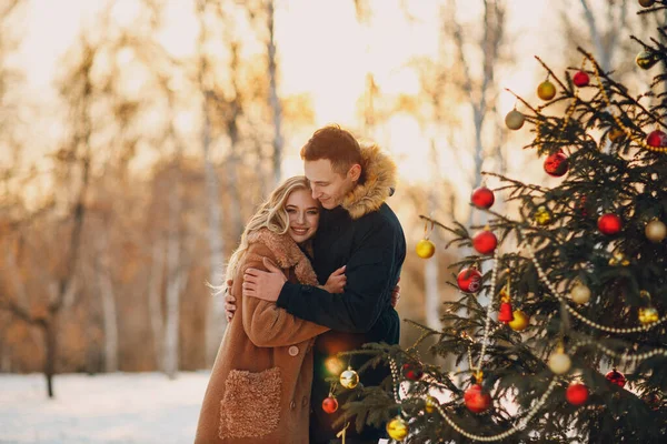 Young adult couple decorates christmas tree in winter forest. New year pine holiday party celebration concept. — Stock Photo, Image