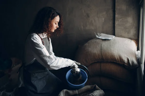 Grãos de café verde em saco de serapilheira e torrador mulher com colher — Fotografia de Stock