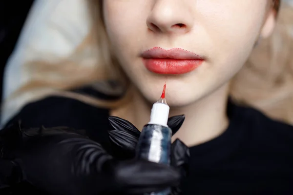 Kozmetik uzmanı genç kadın dudaklarına kalıcı kırmızı makyaj dövmesi yapıyor. Kalıcı dudak dövme prosedürü kavramı. — Stok fotoğraf