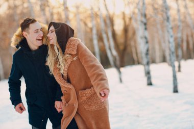 Sevgi dolu genç bir çift kış parkında yürüyor ve eğleniyor.