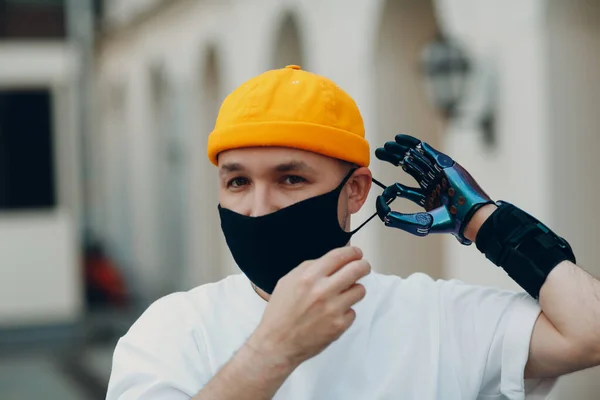 Pemuda cacat mengenakan topeng wajah pelindung medis dengan tangan buatan. — Stok Foto