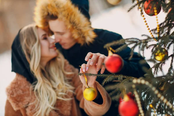 Young adult couple decorates christmas tree in winter forest. New year pine holiday party celebration concept. — Stock Photo, Image