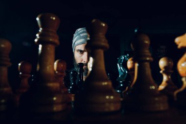 Genç ve yakışıklı bir adam karanlıkta satranç oynuyor.