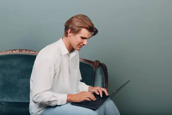 Портрет молодого человека, сидящего с ноутбуком в студии. — стоковое фото
