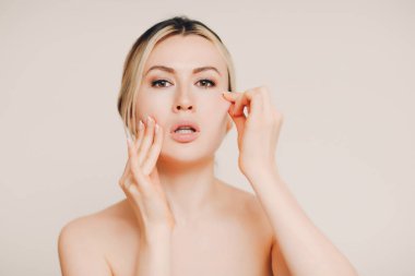 Young adult woman with nude makeup doing facial gymnastics and face skin self massage and rejuvenating exercises facebuilding and lifting. Smooth fresh skin and cosmetics concept