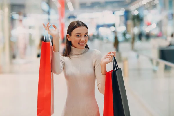 Mujer adulta joven positiva llevando bolsas de papel en las manos —  Fotos de Stock