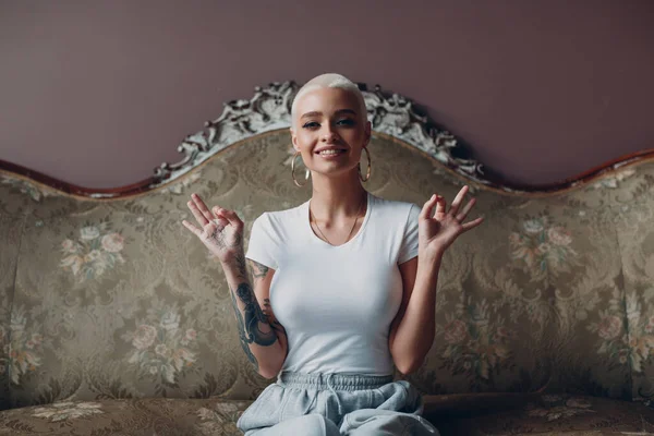 Millenial junge Frau mit kurzen blonden Haaren Porträt sitzt auf Vintage-Sofa. — Stockfoto