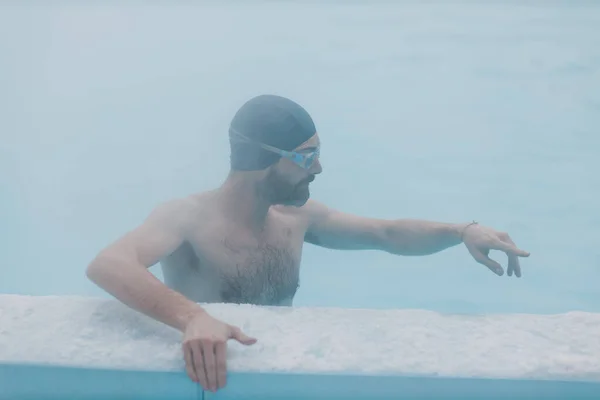 Fit perenang laki-laki pelatihan berenang di kolam renang musim dingin terbuka dengan kabut. Spa konsep Geothermal outdoor. — Stok Foto