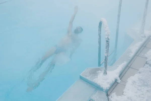 오리너구리 수컷은 겨울에 안개가 끼어 있는 옥외 수영장에서 수영 훈련을 받는다. 지열 실외 온천 개념. — 스톡 사진