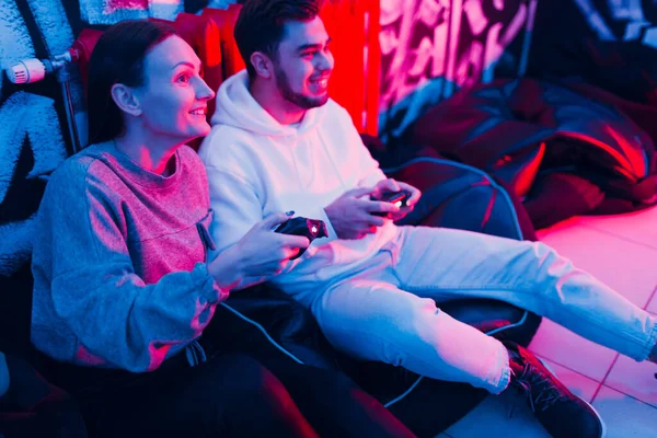Pasangan muda dan wanita bermain di konsol permainan dengan gamepad duduk di kursi — Stok Foto