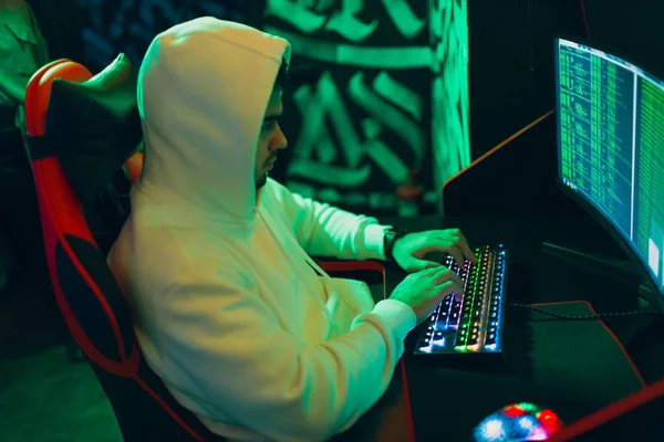 Hacker di hoodie bekerja hacks kode situs di komputer pribadi dengan lampu hijau — Stok Foto