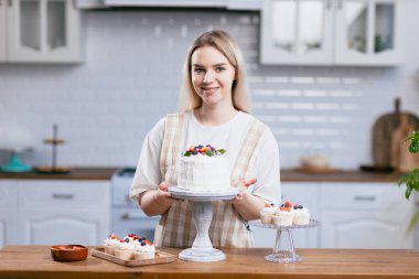 Pasta şefi, mutfak masasında pastası olan beyaz bir kadın..